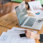 Business woman hand with Financial charts and laptop on the tabl